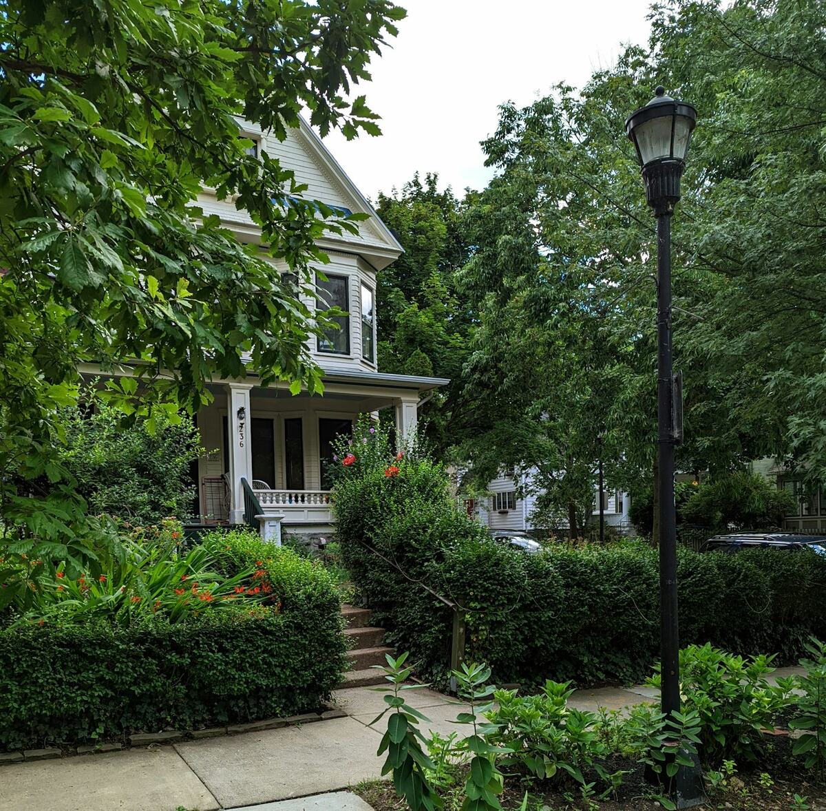 A two-story Buffalo home with a front porch and hedges